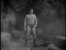Superman standing near a cave