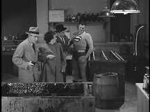 Superman holds Marcel and Inspector Henderson holds Marie; both crime-fighters look into the acid vat