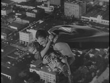 Superman flies over the city with Kathy in his arms